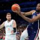 Kevin Durant, right, of the United States, passes the ball as he heads out of bounds while under pressure from Marko Guduric, of Serbia, in a men's basketball game at the 2024 Summer Olympics, Sunday, July 28, 2024, in Villeneuve-d'Ascq, France. (AP Photo/Michael Conroy)