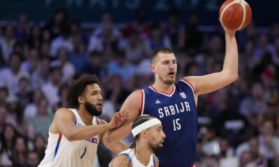 Nikola Jokic, of Serbia, looks to pass away from George Conditt IV, of Puerto Rico, in a men's basketball game at the 2024 Summer Olympics, Wednesday, July 31, 2024, in Villeneuve-d'Ascq, France. (AP Photo/Mark J. Terrill)