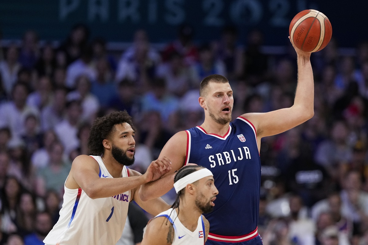 Nikola Jokic, of Serbia, looks to pass away from George Conditt IV, of Puerto Rico, in a men's basketball game at the 2024 Summer Olympics, Wednesday, July 31, 2024, in Villeneuve-d'Ascq, France. (AP Photo/Mark J. Terrill)