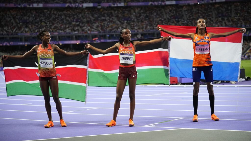 Gold medalist Beatrice Chebet, centre, of Kenya, accompanied by compatriot Faith Kipyegon, poses for a photo with silver medalist Sifan Hassan, right, of the Netherlands, following the women's 5000-meters final at the 2024 Summer Olympics, Monday, Aug. 5, 2024, in Saint-Denis, France. (AP Photo/Petr David Josek)