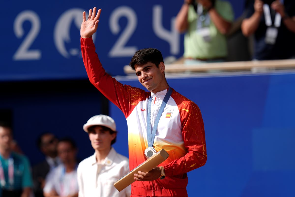 Spain's Carlos Alcaraz waves with his silver medal after losing to Serbia's Novak Djokovic in the men's singles tennis final at the Roland Garros stadium during the 2024 Summer Olympics, Sunday, Aug. 4, 2024, in Paris, France. Djokovic has won his first Olympic gold medal by beating Alcaraz 7-6 (3), 7-6 (2) in the 2024 Games men's tennis singles final. (AP Photo/Manu Fernandez)