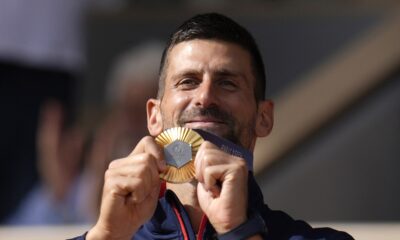 Serbia's Novak Djokovic shows his gold medal after defeating Spain's Carlos Alcaraz in the men's singles tennis final at the Roland Garros stadium during the 2024 Summer Olympics, Sunday, Aug. 4, 2024, in Paris, France. Djokovic has won his first Olympic gold medal by beating Alcaraz 7-6 (3), 7-6 (2) in the 2024 Games men's tennis singles final. (AP Photo/Manu Fernandez)