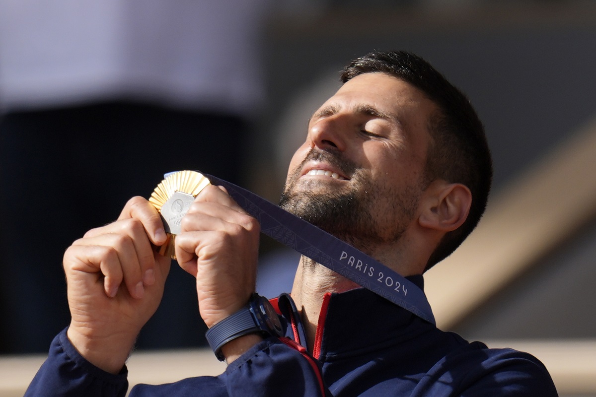 Serbia's Novak Djokovic watches his gold medal after defeating Spain's Carlos Alcaraz in the men's singles tennis final at the Roland Garros stadium during the 2024 Summer Olympics, Sunday, Aug. 4, 2024, in Paris, France. Djokovic has won his first Olympic gold medal by beating Alcaraz 7-6 (3), 7-6 (2) in the 2024 Games men's tennis singles final. (AP Photo/Manu Fernandez)