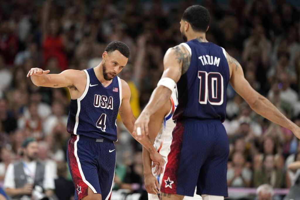 Stephen Curry, left, of the United States, is congratulated by Jayson Tatum, of the United States, after he scored during a men's basketball game against Puerto Rico at the 2024 Summer Olympics, Saturday, Aug. 3, 2024, in Villeneuve-d'Ascq, France. (AP Photo/Michael Conroy)