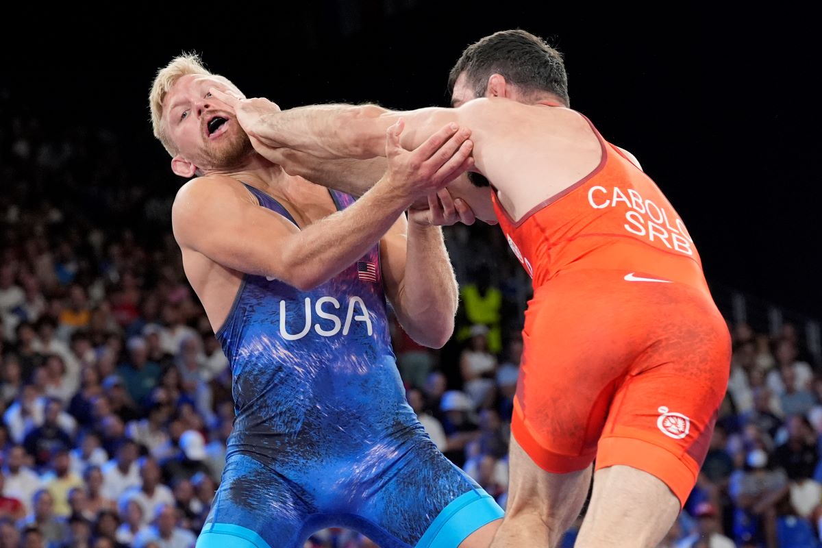 Serbia's Hetik Cabolov and Kyle Douglas Dake, of the United States, in blue, compete during their men's freestyle 74kg bronze medal wrestling match, at Champ-de-Mars Arena, during the 2024 Summer Olympics, Saturday, Aug. 10, 2024, in Paris, France. (AP Photo/Eugene Hoshiko)