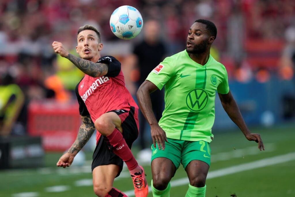 Leverkusen's Alex Grimaldo, left, and Wolfsburg's Ridle Baku fight for the ball during the German Bundesliga soccer match between Bayer Leverkusen and VfL Wolfsburg at the BayArena in Leverkusen, Germany, Sunday, Sept. 22, 2024. (AP Photo/Martin Meissner)