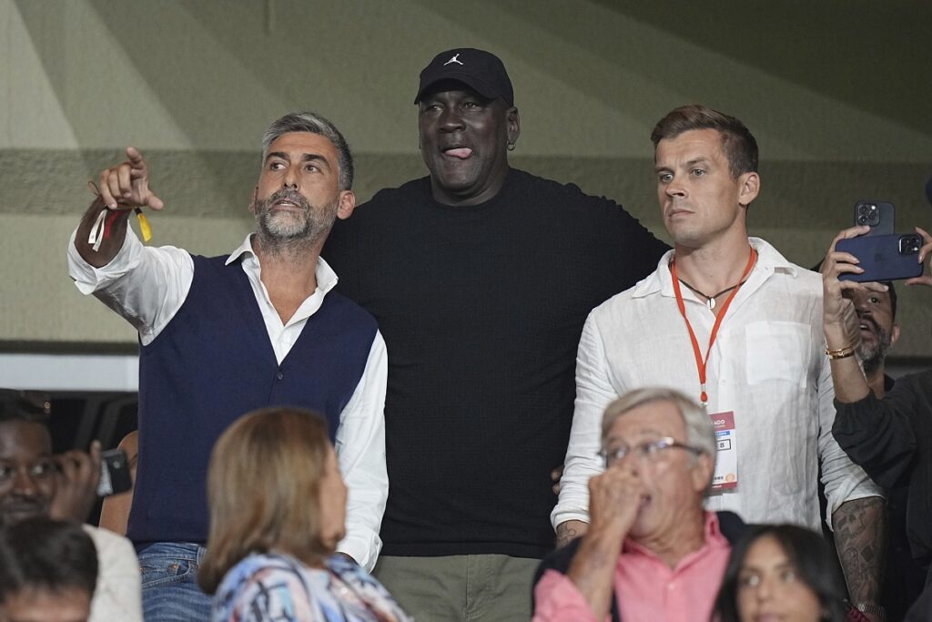 American former professional basketball player Michael Jordan, center, gestures as he attends the Champions League opening phase soccer match between Monaco and Barcelona at the Louis II stadium, in Monaco, Monaco, Thursday, Sept. 19, 2024. (AP Photo/Laurent Cipriani)