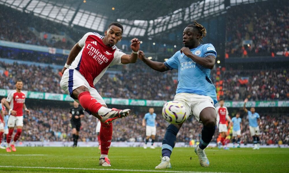 Arsenal's Jurrien Timber, left, clears the ball from Manchester City's Jeremy Doku during the English Premier League soccer match between Manchester City and Arsenal at the Etihad stadium in Manchester, England, Sunday, Sept. 22, 2024. (AP Photo/Dave Thompson)