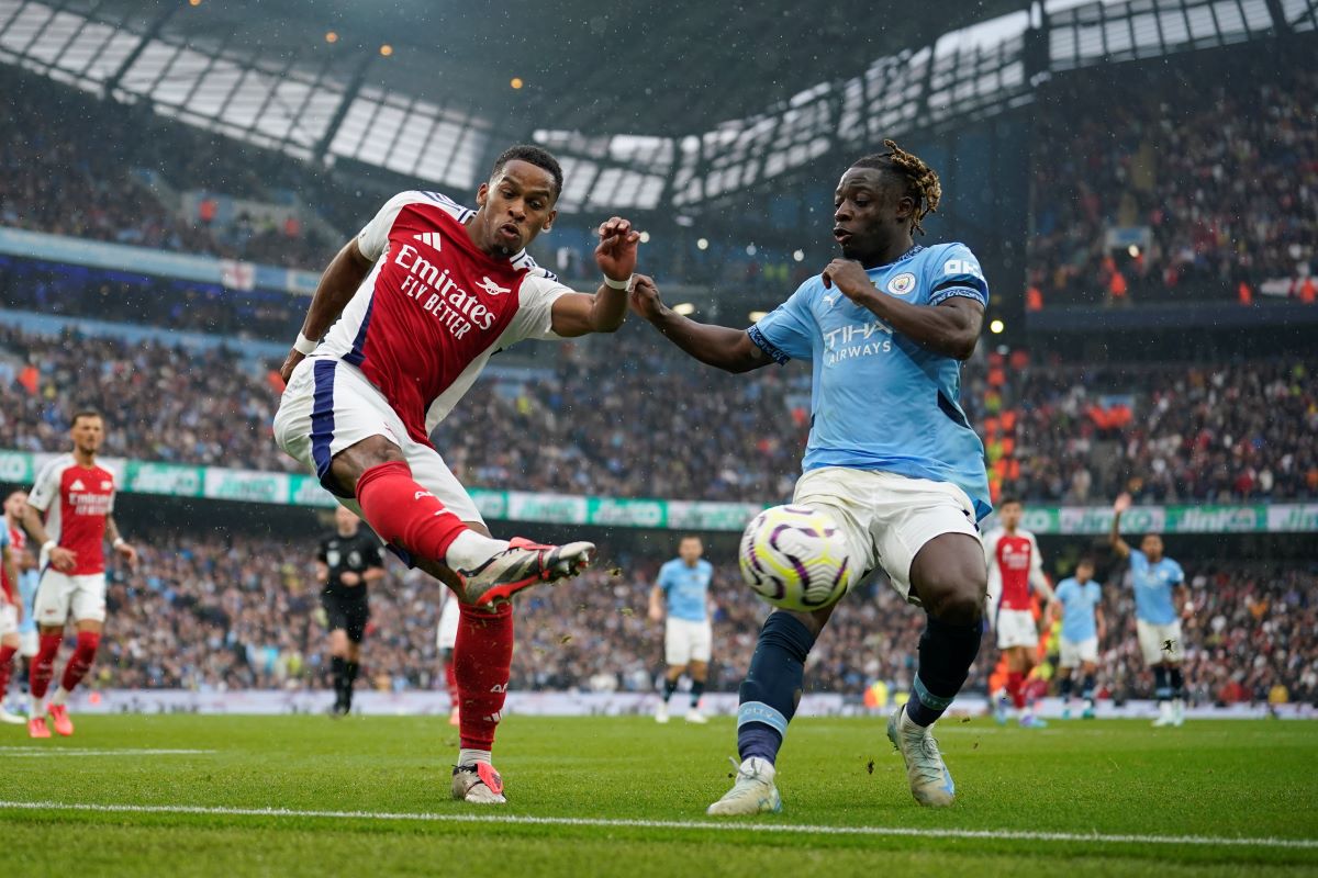 Arsenal's Jurrien Timber, left, clears the ball from Manchester City's Jeremy Doku during the English Premier League soccer match between Manchester City and Arsenal at the Etihad stadium in Manchester, England, Sunday, Sept. 22, 2024. (AP Photo/Dave Thompson)