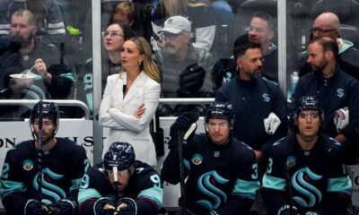 Seattle Kraken assistant coach Jessica Campbell, in white, looks on from the bench during the first period of an NHL hockey game against the St. Louis Blues, Tuesday, Oct. 8, 2024, in Seattle. (AP Photo/Lindsey Wasson)