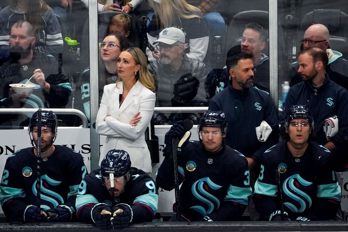 Seattle Kraken assistant coach Jessica Campbell, in white, looks on from the bench during the first period of an NHL hockey game against the St. Louis Blues, Tuesday, Oct. 8, 2024, in Seattle. (AP Photo/Lindsey Wasson)