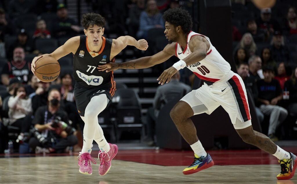 Ratiopharm Ulm guard Ben Saraf, left, dribbles past Portland Trail Blazers guard Scoot Henderson during the first half of a preseason NBA basketball game in Portland, Ore., Wednesday, Oct. 16, 2024. (AP Photo/Craig Mitchelldyer)