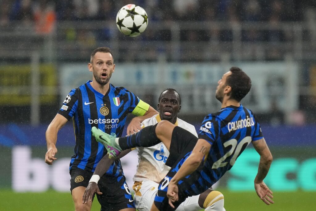 Inter Milan's Hakan Calhanoglu, right, duels for the ball with Red Star's Cherif Ndiaye, center, during the Champions League opening phase soccer match between Inter Milan and Red Star, at the San Siro stadium in Milan, Italy, Tuesday, Oct. 1, 2024. (AP Photo/Luca Bruno)