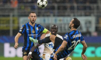 Inter Milan's Hakan Calhanoglu, right, duels for the ball with Red Star's Cherif Ndiaye, center, during the Champions League opening phase soccer match between Inter Milan and Red Star, at the San Siro stadium in Milan, Italy, Tuesday, Oct. 1, 2024. (AP Photo/Luca Bruno)