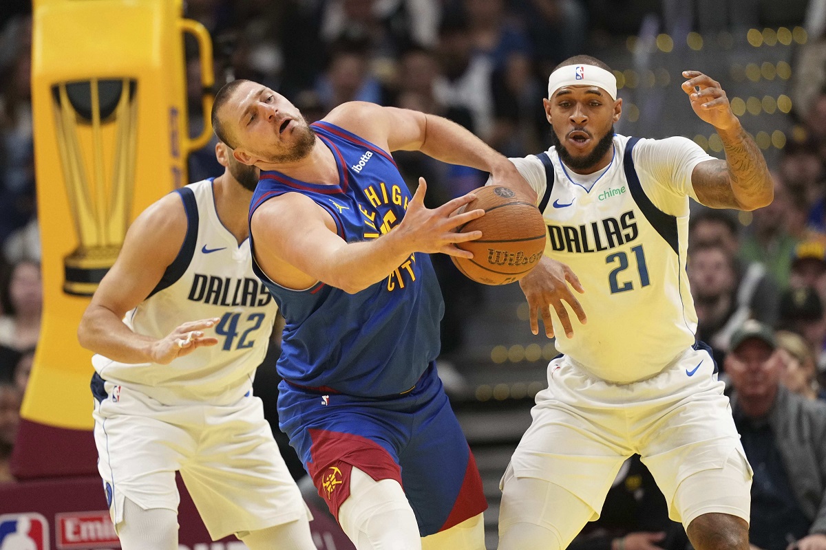 Denver Nuggets center Nikola Jokic, center, bobbles the ball against Dallas Mavericks center Daniel Gafford (21) during the first half of an Emirates NBA Cup basketball game Friday, Nov. 22, 2024, in Denver. (AP Photo/Jack Dempsey)