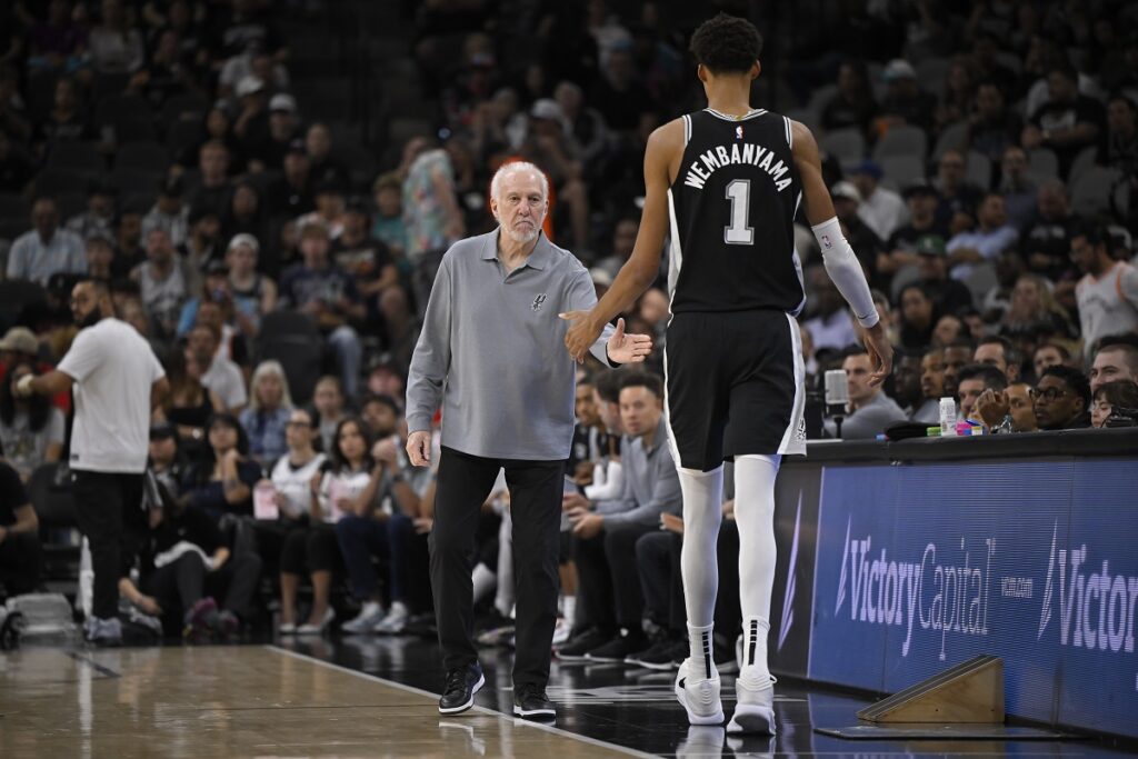 San Antonio Spurs head coach Gregg Popovich, left, greets Spurs forward Victor Wembanyama as he walks off of the court during the first half of an NBA basketball game against the Houston Rockets, Monday, Oct. 28, 2024, in San Antonio. (AP Photo/Darren Abate)