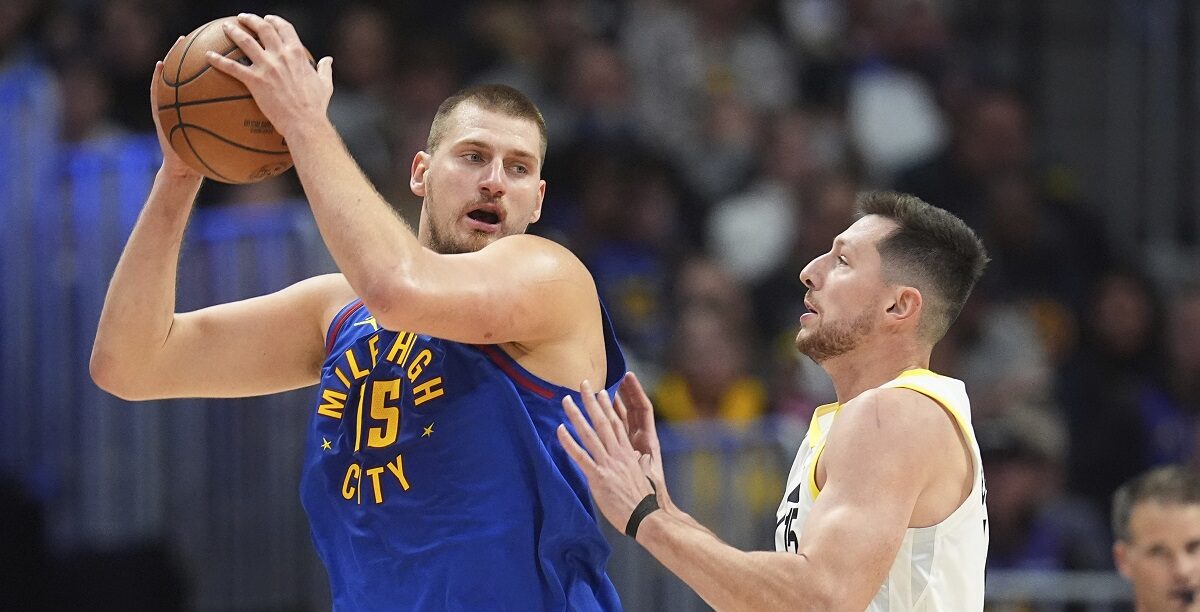 Denver Nuggets center Nikola Jokic, left, looks to pass the ball as Utah Jazz forward Drew Eubanks defends in the second half of an NBA basketball game Saturday, Nov. 2, 2024, in Denver. (AP Photo/David Zalubowski)