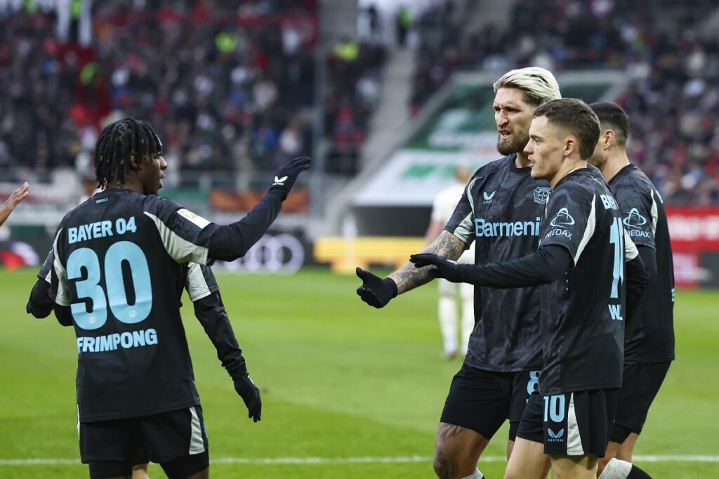 From left, Jeremie Frimpong, Robert Andrich and Florian Wirtz of Bayer Leverkusen celebrate after scoring their side's first goal during the Bundesliga soccer match between FC Augsburg and Bayer Leverkusen at the WWK-Arena in Augsburg, Germany, Saturday, Dec. 14, 2024. (Daniel Löb/dpa via AP)