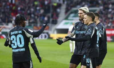 From left, Jeremie Frimpong, Robert Andrich and Florian Wirtz of Bayer Leverkusen celebrate after scoring their side's first goal during the Bundesliga soccer match between FC Augsburg and Bayer Leverkusen at the WWK-Arena in Augsburg, Germany, Saturday, Dec. 14, 2024. (Daniel Löb/dpa via AP)