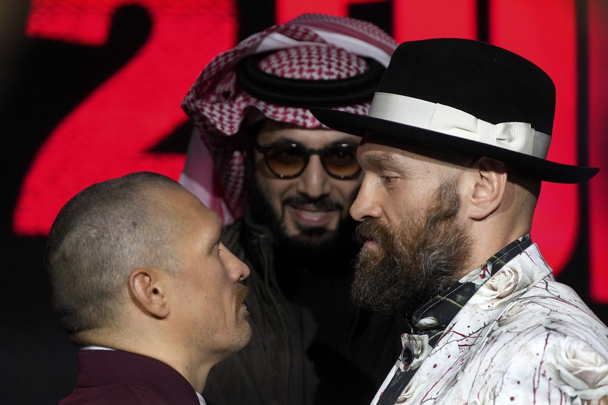 Boxer Tyson Fury, right, and Oleksandr Usyk, left, face off under the eyes of Turki Al-Sheik during a press conference in Riyadh, Saudi Arabia, Thursday, Dec. 19, 2024 ahead of the WBA, WBO, and WBC heavyweight title bout between Britain's Tyson Fury and Ukraine's Oleksandr Usyk. (AP Photo/Frank Augstein)