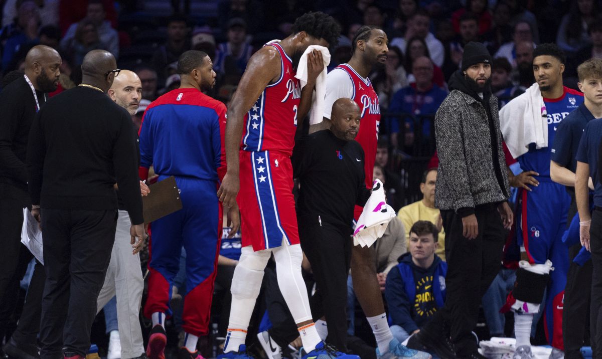 Philadelphia 76ers' Joel Embiid, center, gets helped off the court after getting hit in the face during the first half of an NBA basketball game against the Indiana Pacers, Friday, Dec. 13, 2024, in Philadelphia. (AP Photo/Chris Szagola)