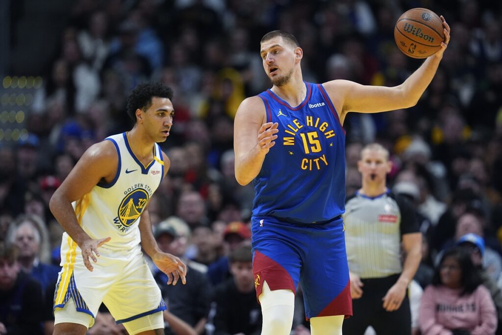 Denver Nuggets center Nikola Jokic, right, pulls in a pass as Golden State Warriors forward Trayce Jackson-Davis defends in the second half of an Emirates NBA Cup basketball game Tuesday, Dec. 3, 2024, in Denver. (AP Photo/David Zalubowski)