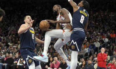 Phoenix Suns forward Kevin Durant drives between Denver Nuggets center Nikola Jokic (15) and forward Peyton Watson during the second half of an NBA basketball game, Wednesday, Dec. 25, 2024, in Phoenix. Phoenix won 110-100. (AP Photo/Rick Scuteri)