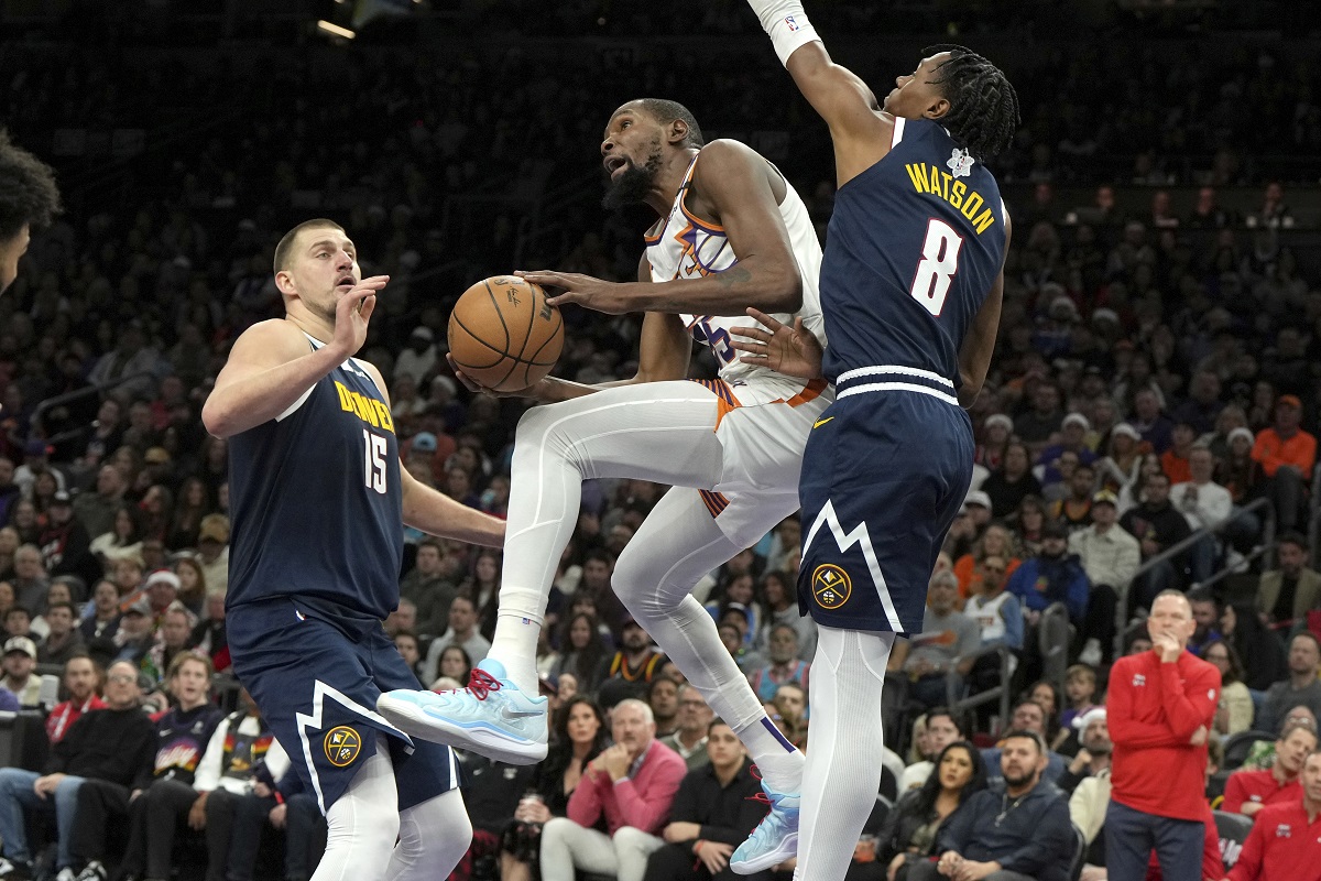 Phoenix Suns forward Kevin Durant drives between Denver Nuggets center Nikola Jokic (15) and forward Peyton Watson during the second half of an NBA basketball game, Wednesday, Dec. 25, 2024, in Phoenix. Phoenix won 110-100. (AP Photo/Rick Scuteri)