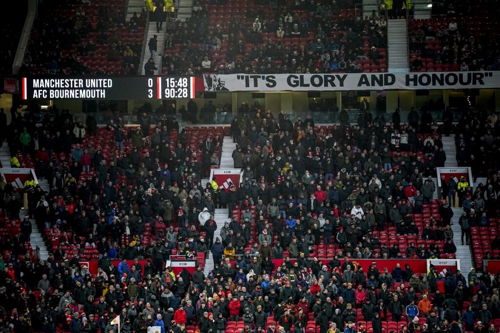 Spectators watch from the stands after the English Premier League soccer match between Manchester United and Bournemouth at the Old Trafford stadium in Manchester, England, Sunday, Dec. 22, 2024. (AP Photo/Dave Thompson)