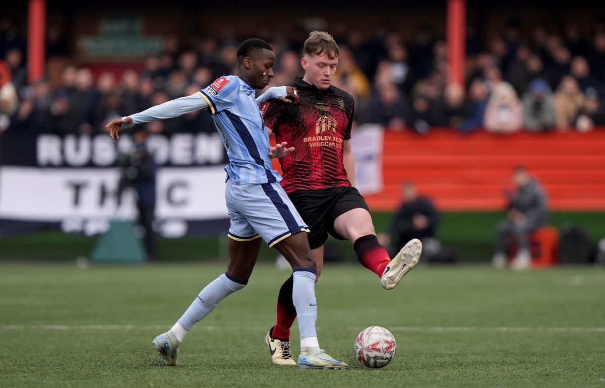 Tottenham Hotspur's Pape Matar Sarr, left, and Tamworth's Daniel Creaney battle for the ball during the English FA Cup third round match at The Lamb Ground, Tamworth, England, Sunday Jan. 12, 2025. (Joe Giddens/PA via AP)