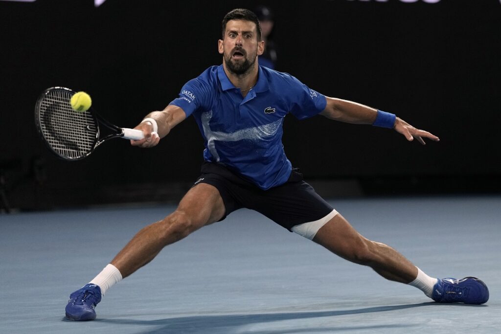 Novak Djokovic of Serbia plays a forehand return to Carlos Alcaraz of Spain during their quarterfinal match at the Australian Open tennis championship in Melbourne, Australia, Wednesday, Jan. 22, 2025. (AP Photo/Ng Han Guan)