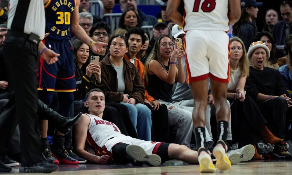 Miami Heat forward Nikola Jovic, bottom, reacts after making a 3-point basket and being fouled by Golden State Warriors guard Stephen Curry (30) during the second half of an NBA basketball game Tuesday, Jan. 7, 2025, in San Francisco. (AP Photo/Godofredo A. Vásquez)