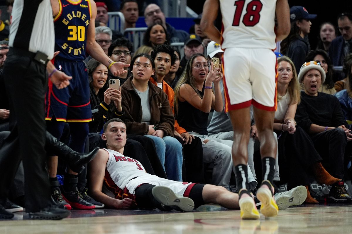 Miami Heat forward Nikola Jovic, bottom, reacts after making a 3-point basket and being fouled by Golden State Warriors guard Stephen Curry (30) during the second half of an NBA basketball game Tuesday, Jan. 7, 2025, in San Francisco. (AP Photo/Godofredo A. Vásquez)