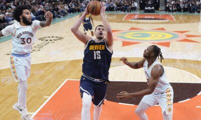 Denver Nuggets center Nikola Jokic (15) drives to the basket past San Antonio Spurs forward Julian Champagnie (30) and center Charles Bassey, right, during the first half of an NBA basketball game in San Antonio, Saturday, Jan. 4, 2025. (AP Photo/Eric Gay)