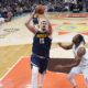 Denver Nuggets center Nikola Jokic (15) drives to the basket past San Antonio Spurs forward Julian Champagnie (30) and center Charles Bassey, right, during the first half of an NBA basketball game in San Antonio, Saturday, Jan. 4, 2025. (AP Photo/Eric Gay)