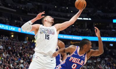 Denver Nuggets center Nikola Jokic, left, pulls in a rebound over Philadelphia 76ers guard Tyrese Maxey in the second half of an NBA basketball game Tuesday, Jan. 21, 2025, in Denver. (AP Photo/David Zalubowski)