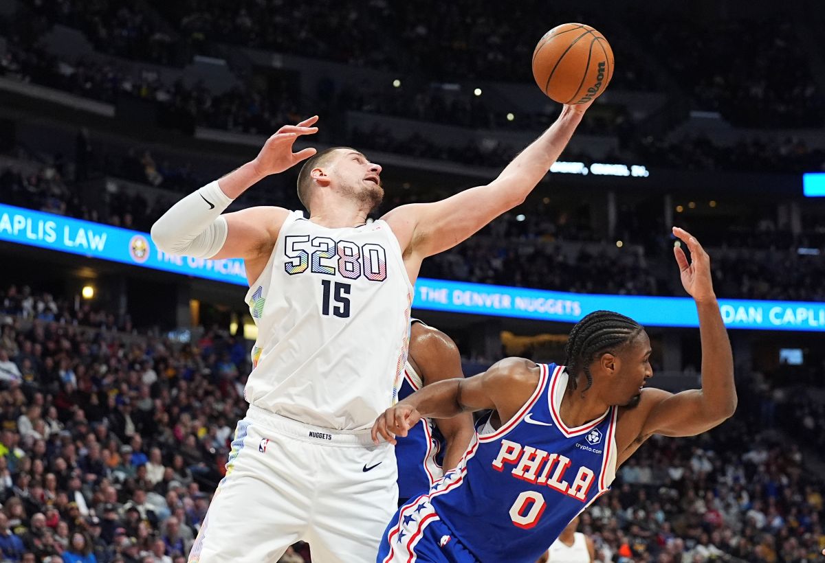 Denver Nuggets center Nikola Jokic, left, pulls in a rebound over Philadelphia 76ers guard Tyrese Maxey in the second half of an NBA basketball game Tuesday, Jan. 21, 2025, in Denver. (AP Photo/David Zalubowski)