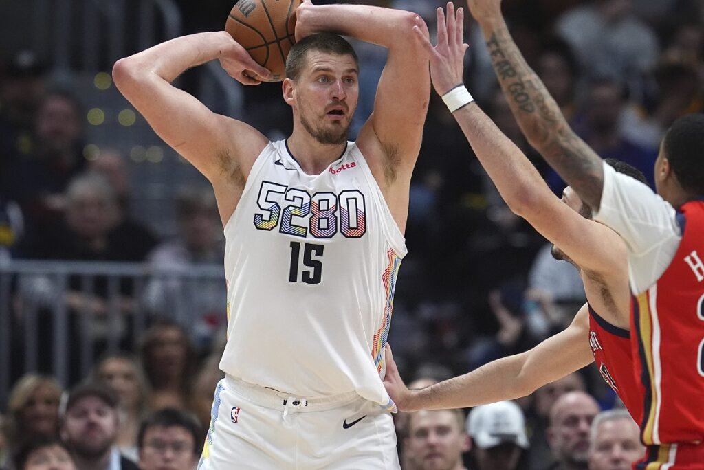 Denver Nuggets center Nikola Jokic, left, looks to pass the ball as New Orleans Pelicans guard Jordan Hawkins defends in the second half of an NBA basketball game Wednesday, Feb. 5, 2025, in Denver. (AP Photo/David Zalubowski)