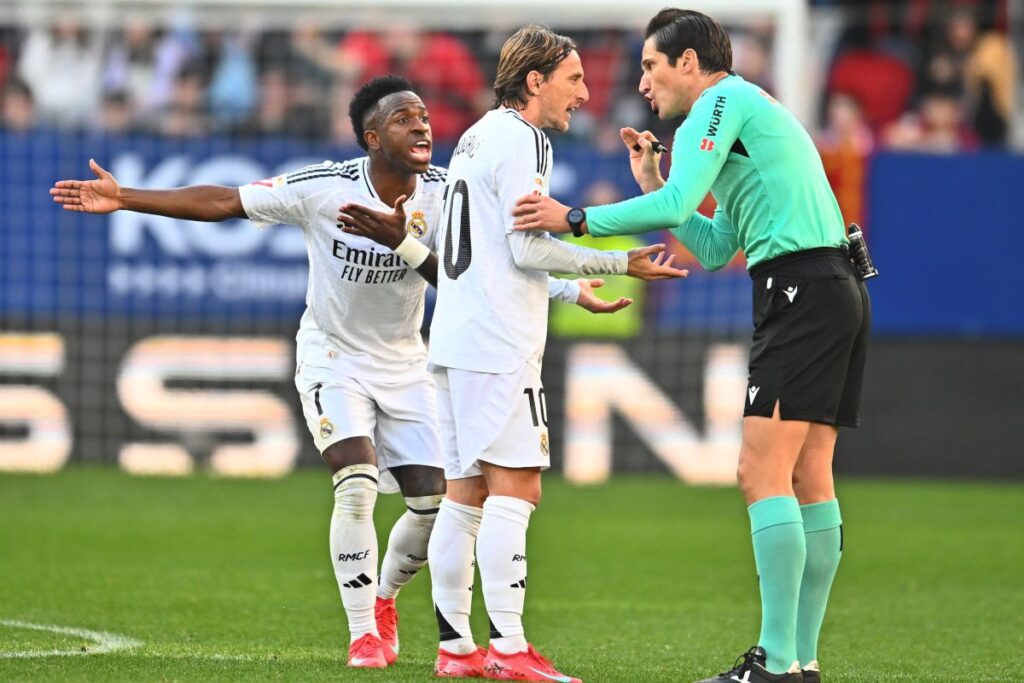 Real Madrid's Luka Modric, centre, speaks with the referee as Vinicius Junior protests during a Spanish La Liga soccer match between Osasuna and Real Madrid at El Sardar stadium in Pamplona, Spain, Saturday, Feb. 15, 2025. (AP Photo/Miguel Oses)