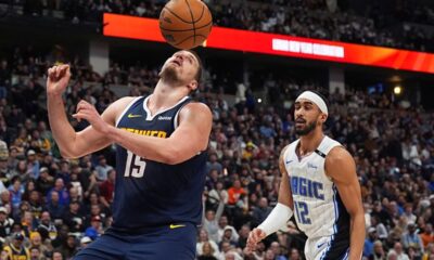 Denver Nuggets center Nikola Jokic, left, avoids the ball after dunking it for a basket as Orlando Magic guard Trevelin Queen looks on in the second half of an NBA basketball game Thursday, Feb. 6, 2025, in Denver. (AP Photo/David Zalubowski)