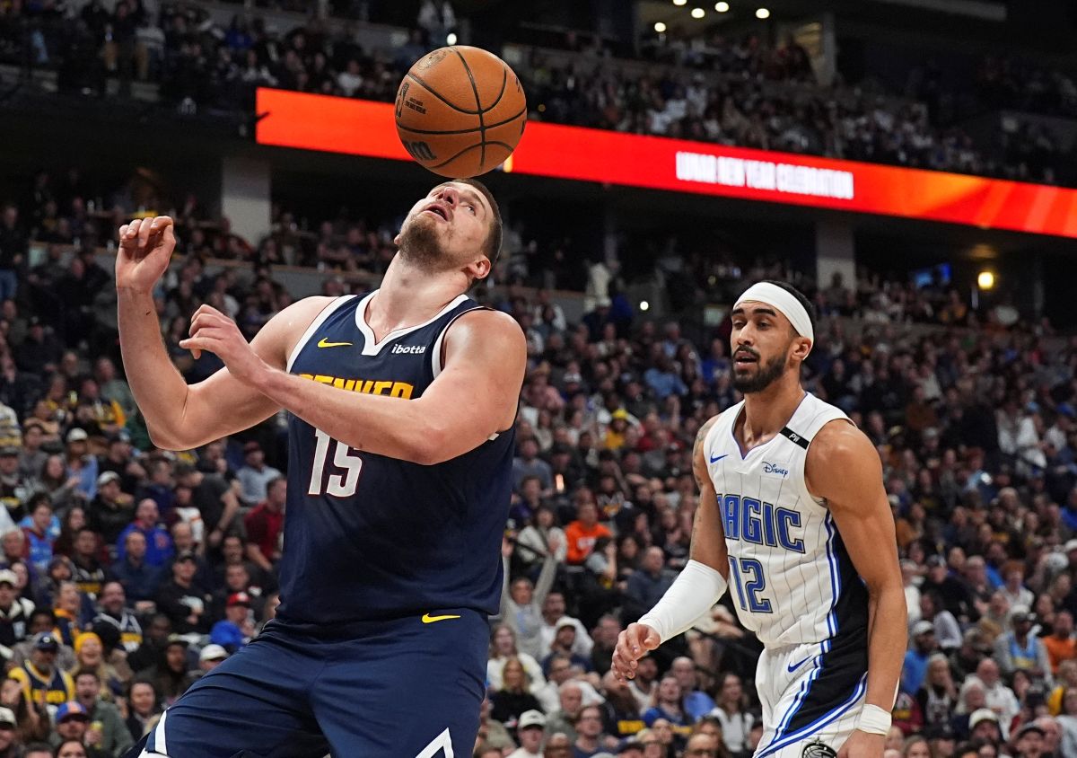 Denver Nuggets center Nikola Jokic, left, avoids the ball after dunking it for a basket as Orlando Magic guard Trevelin Queen looks on in the second half of an NBA basketball game Thursday, Feb. 6, 2025, in Denver. (AP Photo/David Zalubowski)