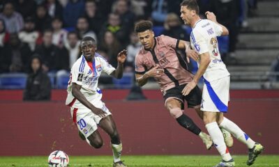 PSG's Desire Doue, center, duels for the ball with Lyon's Nemanja Matic, right, and Lyon's Sael Kumbedi during the French League One soccer match between Lyon and Paris Saint-Germain at the Groupama stadium, outside Lyon, France, Sunday, Feb. 23, 2025. (AP Photo/Laurent Cipriani)