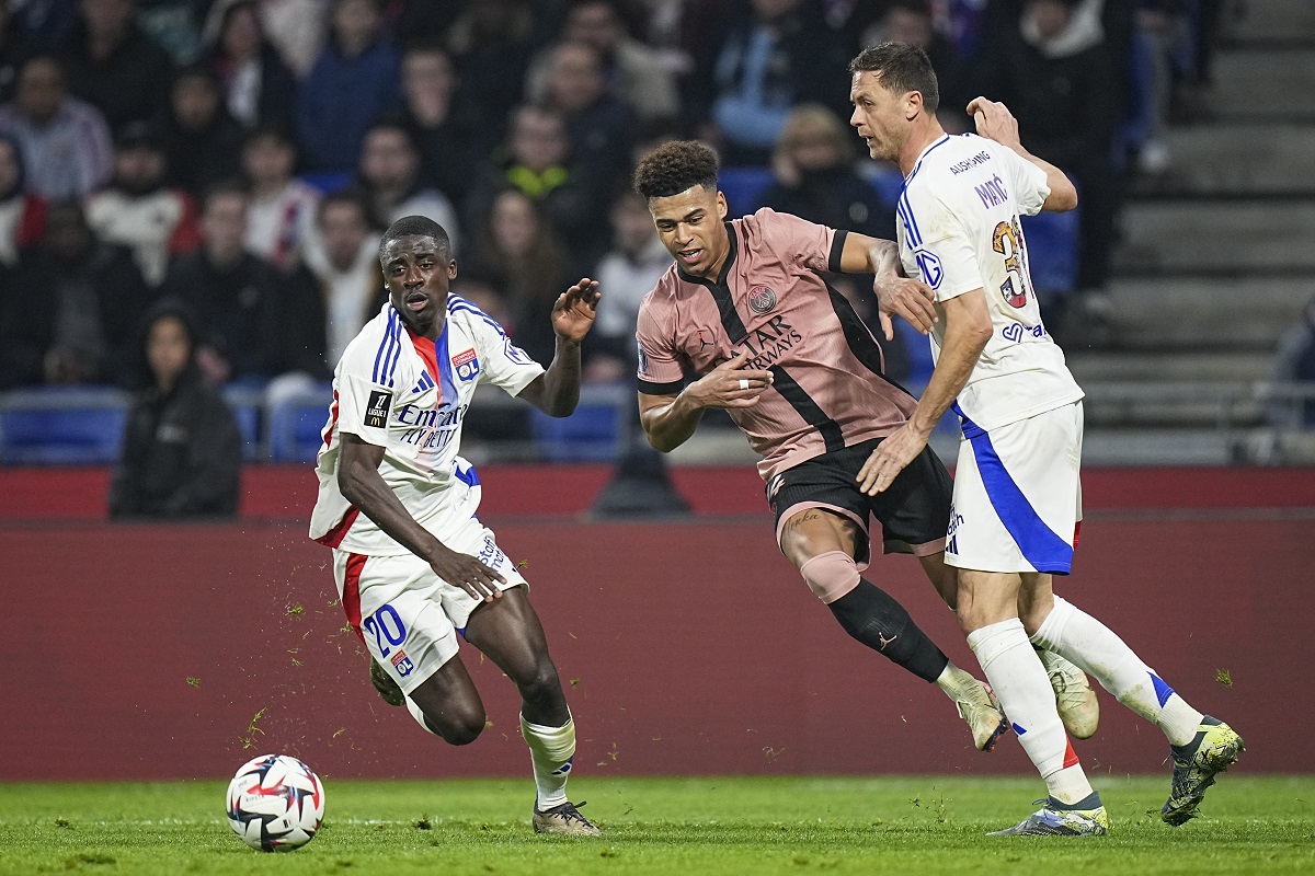 PSG's Desire Doue, center, duels for the ball with Lyon's Nemanja Matic, right, and Lyon's Sael Kumbedi during the French League One soccer match between Lyon and Paris Saint-Germain at the Groupama stadium, outside Lyon, France, Sunday, Feb. 23, 2025. (AP Photo/Laurent Cipriani)