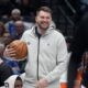 Injured Dallas Mavericks guard Luka Doncic smiles as he holds the game ball in a time out during the first half of an NBA basketball game against the Minnesota Timberwolves Wednesday, Jan. 22, 2025, in Dallas. (AP Photo/LM Otero)