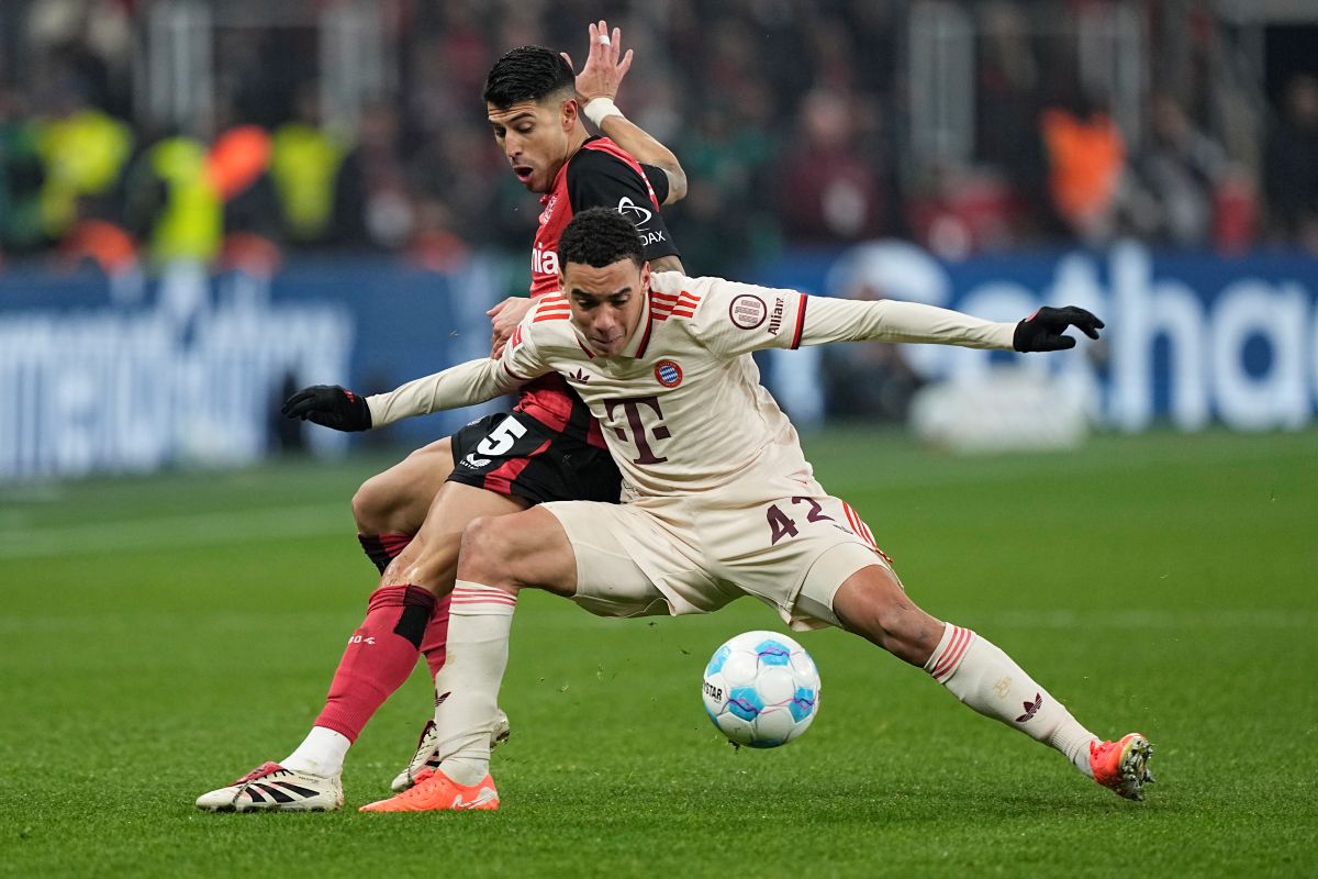 Bayern's Jamal Musiala, right, challenges for the ball with Leverkusen's Exequiel Palacios during the German Bundesliga soccer match between Bayer Leverkusen and FC Bayern Munich at the BayArena in Leverkusen, Germany, Saturday, Feb. 15, 2025. (AP Photo/Martin Meissner)