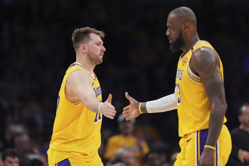 Los Angeles Lakers guard Luka Doncic, left, touches hands with teammate forward LeBron James during the first half of an NBA basketball game against the Utah Jazz, Monday, Feb. 10, 2025, in Los Angeles. (AP Photo/Mark J. Terrill)