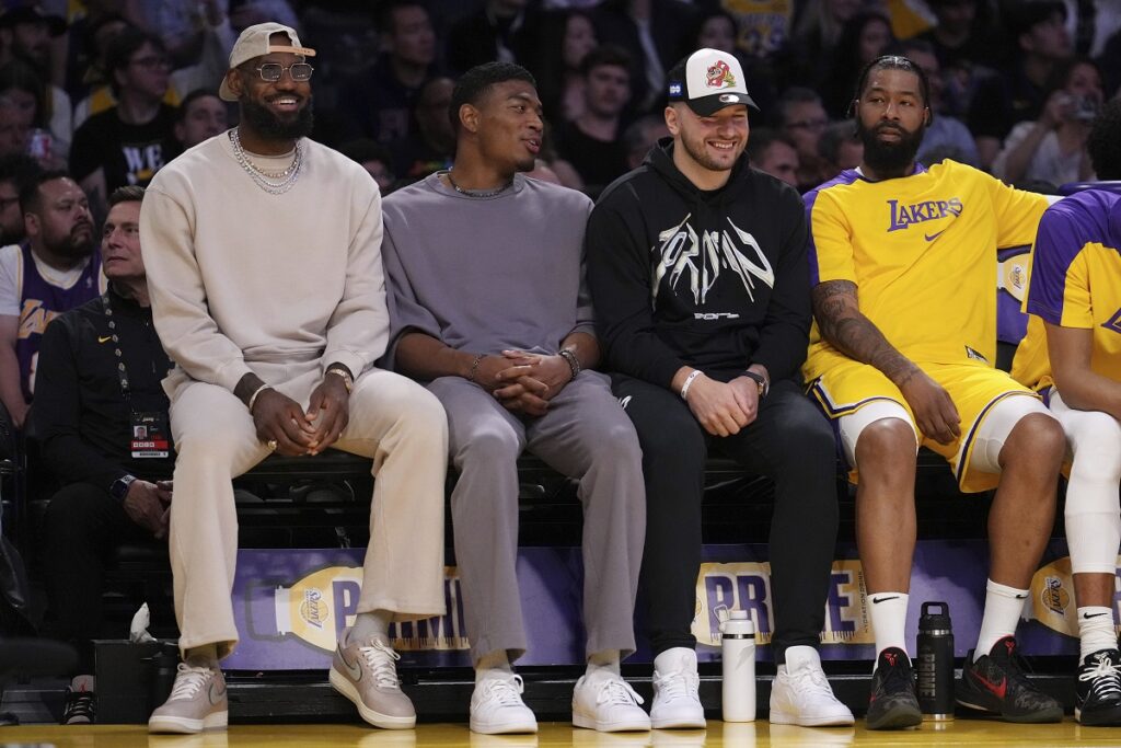 Los Angeles Lakers forward LeBron James, left, forward Rui Hachimura, second from left, guard Luka Doncic, second from right, and forward Markieff Morris sit on the bench during the first half of an NBA basketball game against the Milwaukee Bucks Thursday, March 20, 2025, in Los Angeles. (AP Photo/Mark J. Terrill)