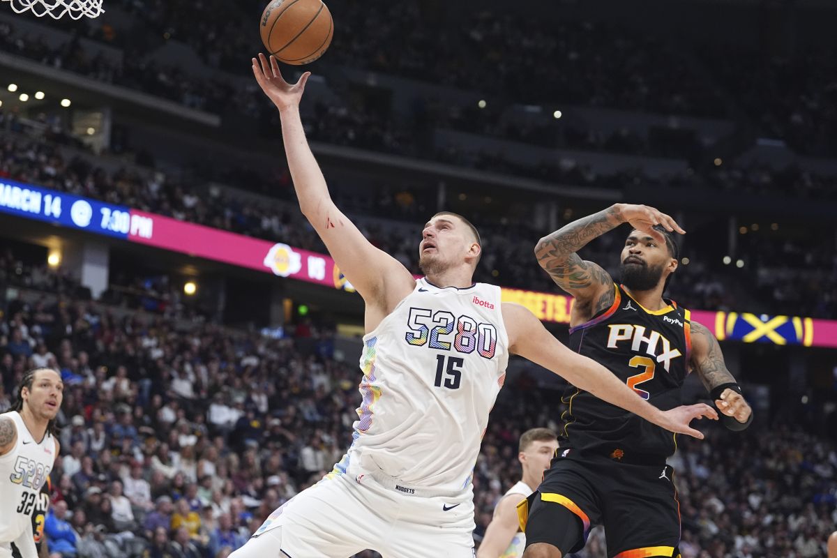 Denver Nuggets center Nikola Jokic (15) pulls in a rebound as Phoenix Suns center Nick Richards defends in the second half of an NBA basketball game Friday, March 7, 2025, in Denver. (AP Photo/David Zalubowski)