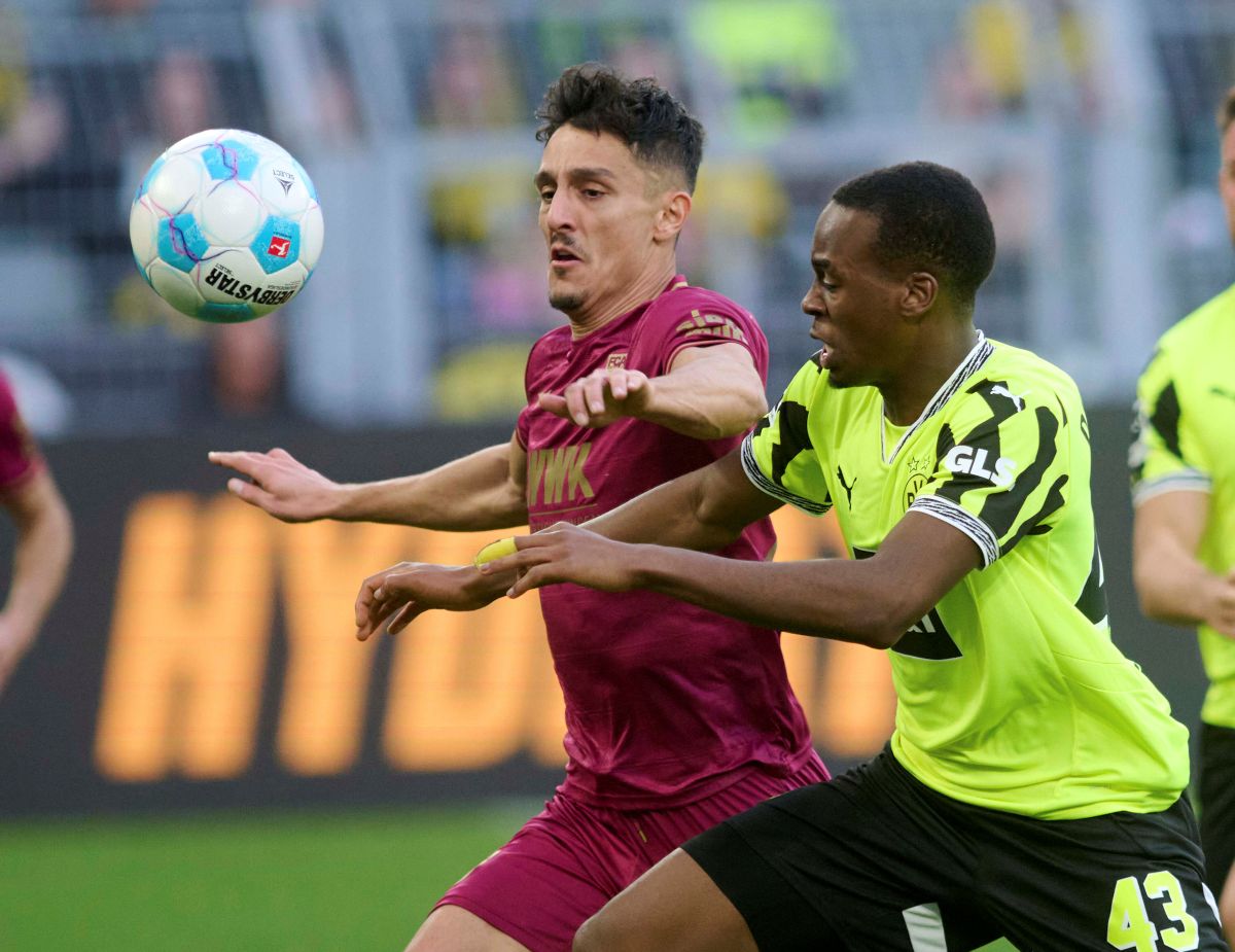 Dortmund's Jamie Gittens, right, and Augsburg's Dimitris Giannoulis in action during the German Bundesliga soccer match between Borussia Dortmund and FC Augsburg at the Signal Iduna Park in Dortmund, Germany, Saturday, March 8, 2025. (Bernd Thissen/dpa via AP)