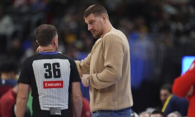 Injured Denver Nuggets center Nikola Jokic, center, confers with referee Brent Barnaky in the second half of an NBA basketball game against the Chicago Bulls, Monday, March 24, 2025, in Denver. (AP Photo/David Zalubowski)